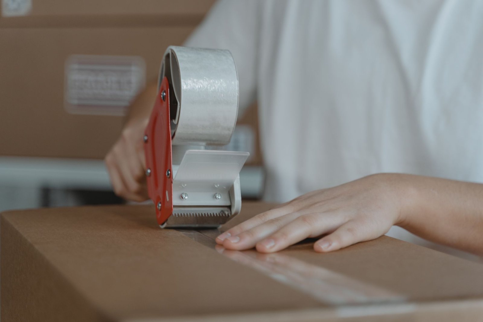 Close view of hands sealing a corrugated shipping box with clear tape