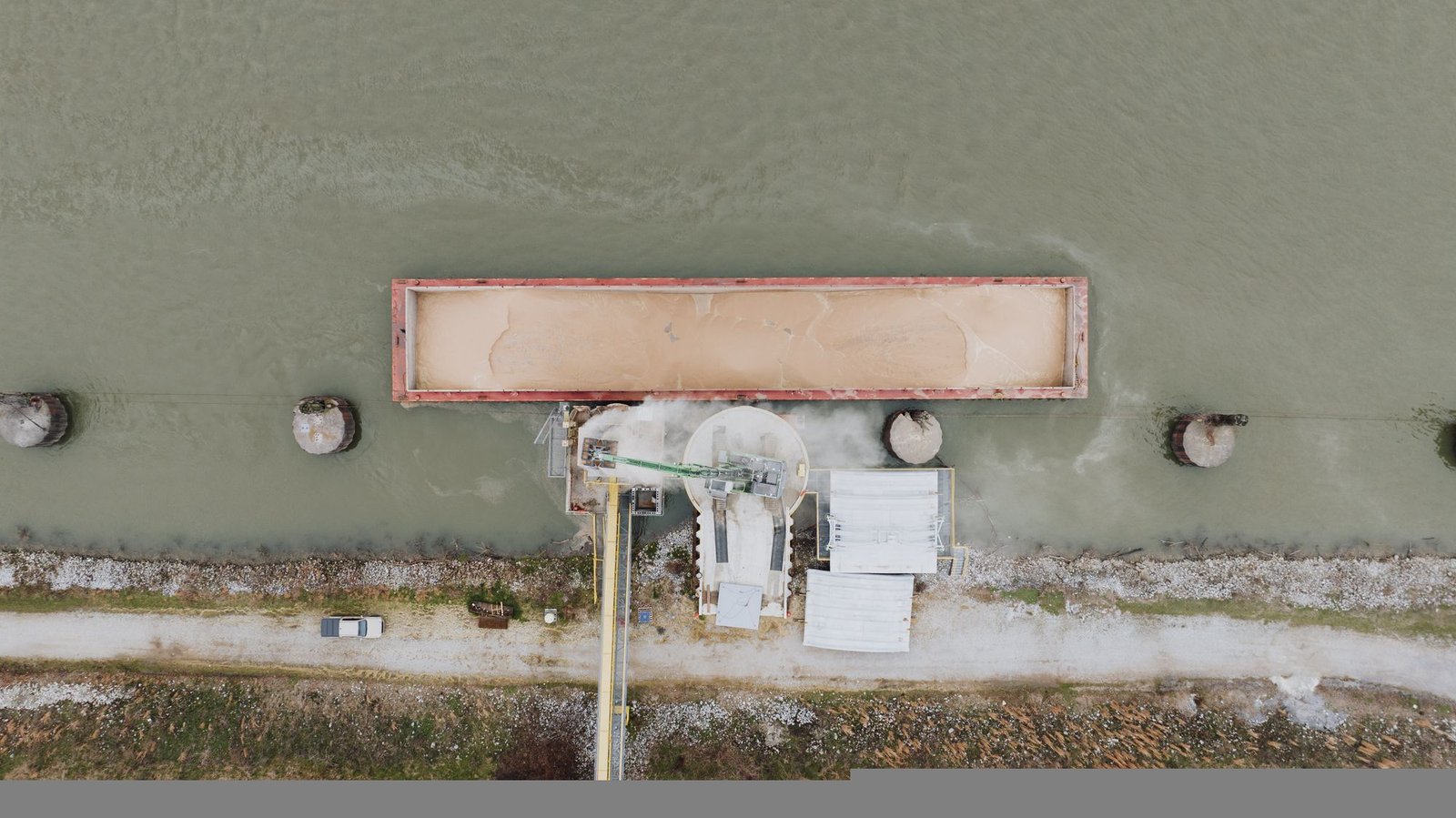 Aerial view of a cargo barge beside an industrial river loading terminal